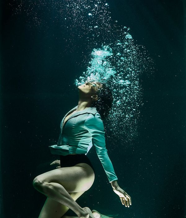 A person in a fluid motion pose against a light linen background.